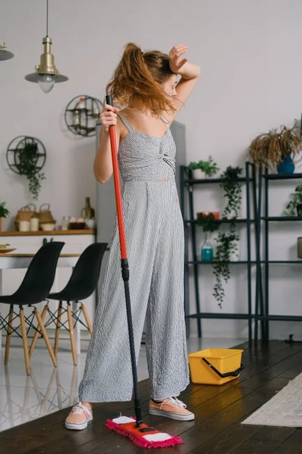 A professional cleaner in protective gear vacuuming the floor in a modern living room.